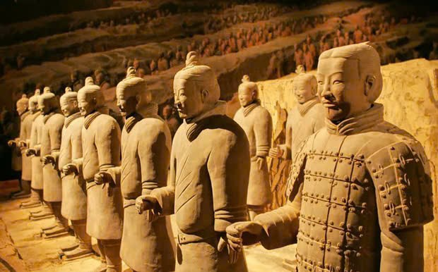Đứng thẳng trong đội hình, hai tay đưa về phía trước để cầm vũ khí, giữ tư thế ổn định và sẵn sàng chiến đấu khi có lệnh.
